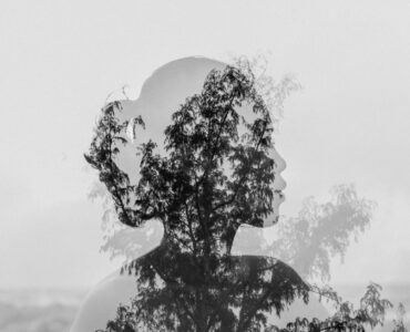 silhouette of asian woman behind tree branch near endless ocean