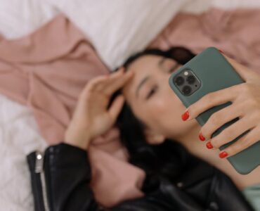 woman lying in bed taking selfie on phone