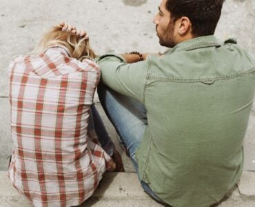 man and woman sitting on sidewalk