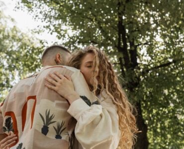 a man and woman hugging under a tree